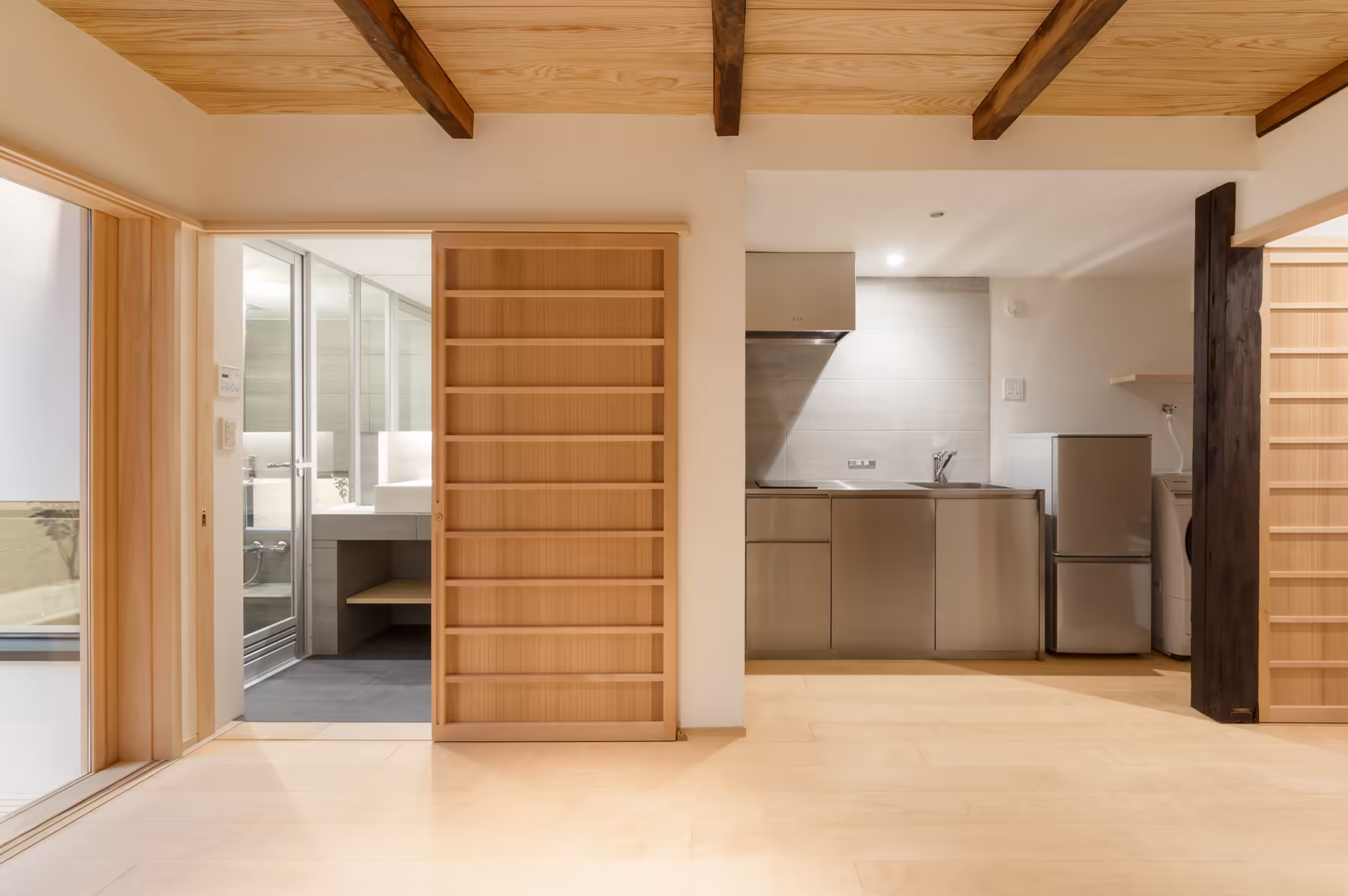 The kitchen along the hallway — stainless counter and fridge set between cedar shelving