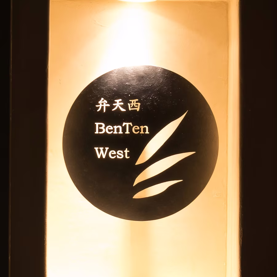 The name plate of BenTen West, 弁天西, lit from above in a wall recess by the door
