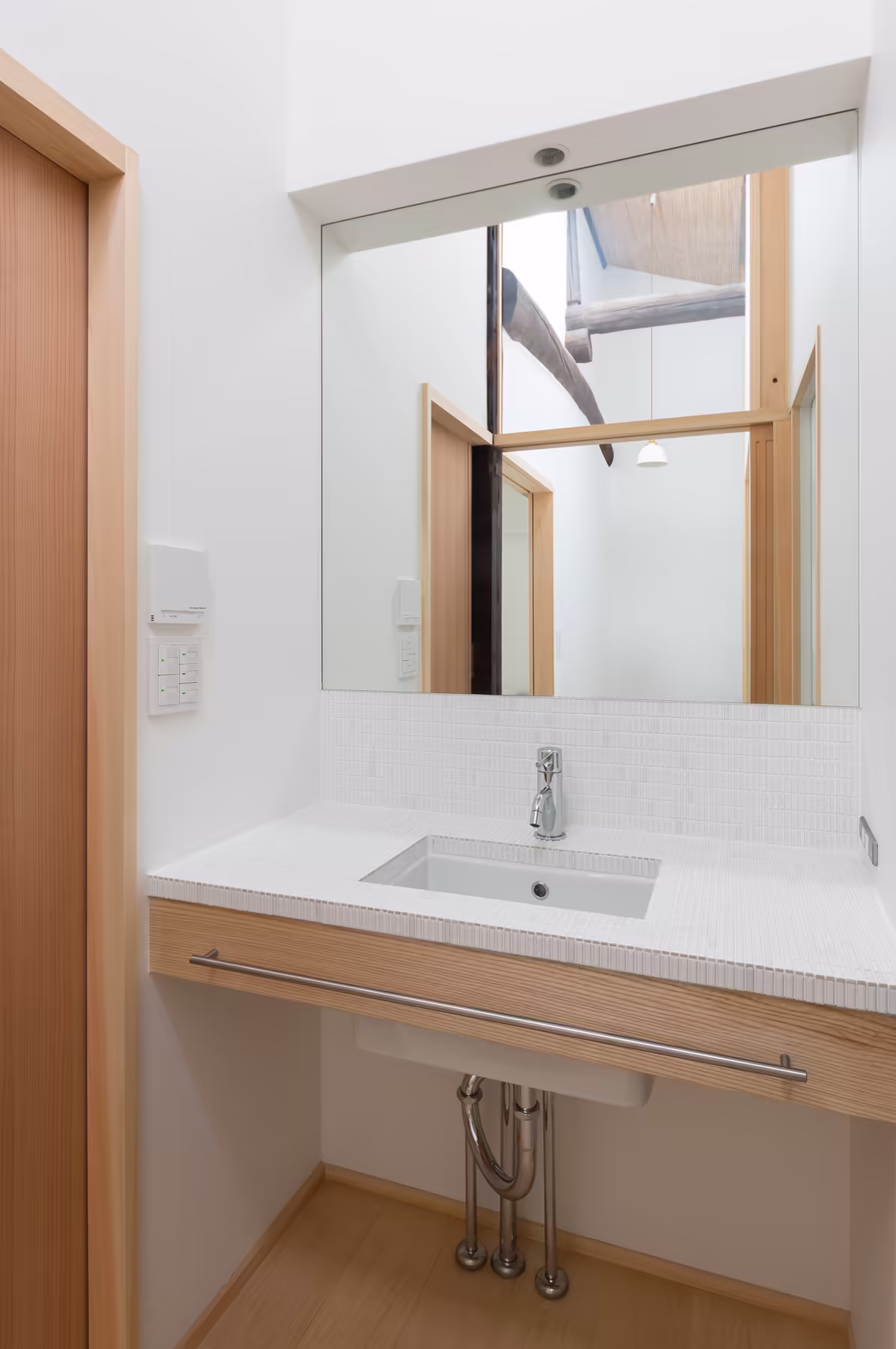 The washbasin and mirror, set into pale timber beside the bathroom
